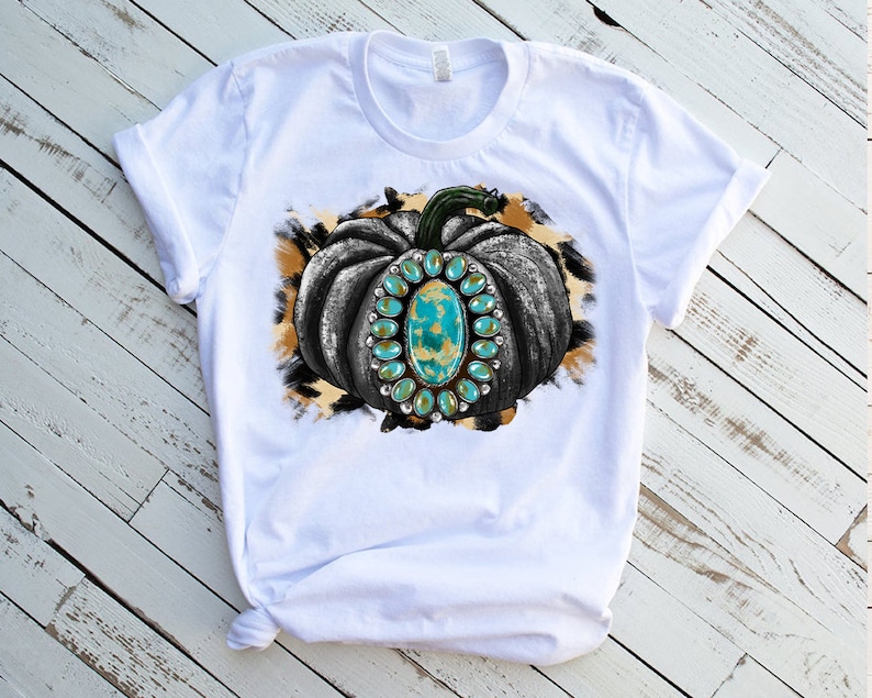 Puede incluir: Camiseta blanca con un gr&aacute;fico de una calabaza en blanco y negro con piedras preciosas turquesa sobre un fondo de estampado de leopardo marr&oacute;n y blanco.