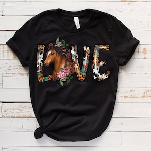 May include: Black t-shirt with a graphic of the word "LOVE" in colorful letters with a horse head and floral design.