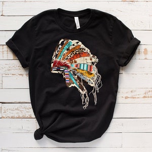 Pu&ograve; includere: Maglietta nera con un design colorato di copricapo nativo americano. Il copricapo &egrave; fatto di piume, perline e pelle.