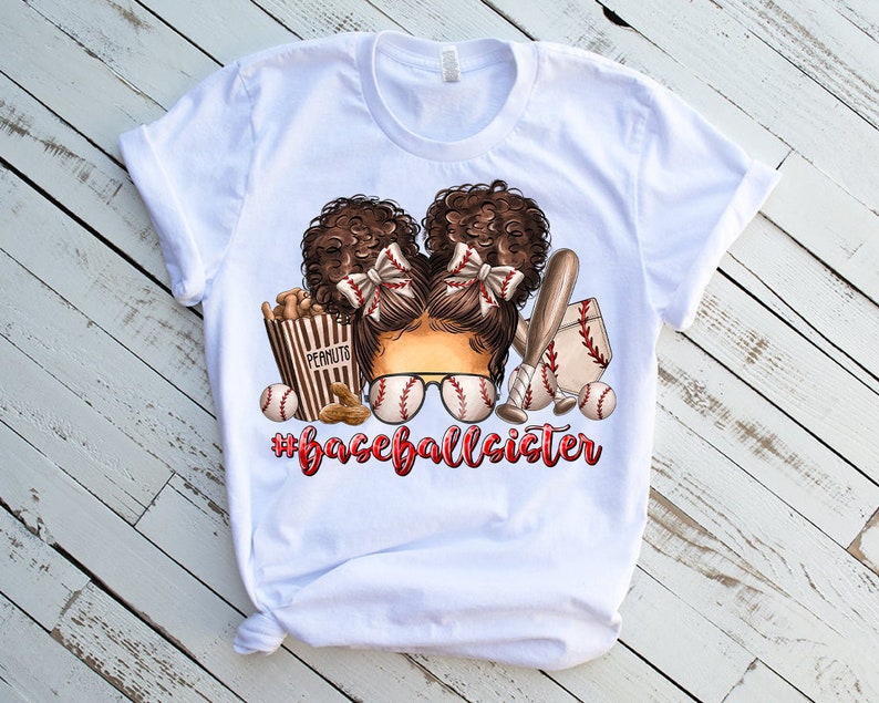 Peut inclure: T-shirt blanc avec un motif repr&eacute;sentant une fille aux cheveux bruns portant des lunettes de soleil de baseball et un n&oelig;ud rouge. Le motif comprend &eacute;galement des balles de baseball, une batte et une bo&icirc;te de cacahu&egrave;tes. Le texte "#baseballsister" est imprim&eacute; sous le motif.