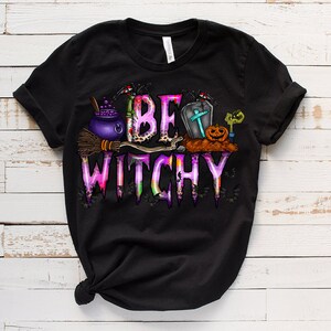 May include: Black t-shirt with a pink and purple graphic that says "Be Witchy" with a cauldron, broom, and other Halloween imagery.
