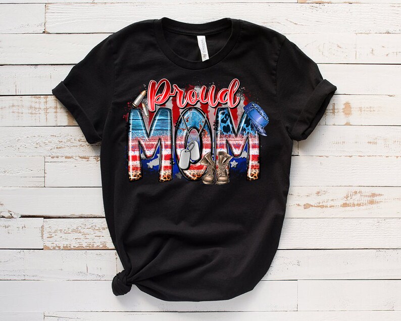 Może przedstawiać: Czarny T-shirt z nadrukiem graficznym sł&oacute;w "Proud Mom" w kolorze czerwonym, białym i niebieskim z wzorem amerykańskiej flagi, wojskowymi identyfikatorami i butami.