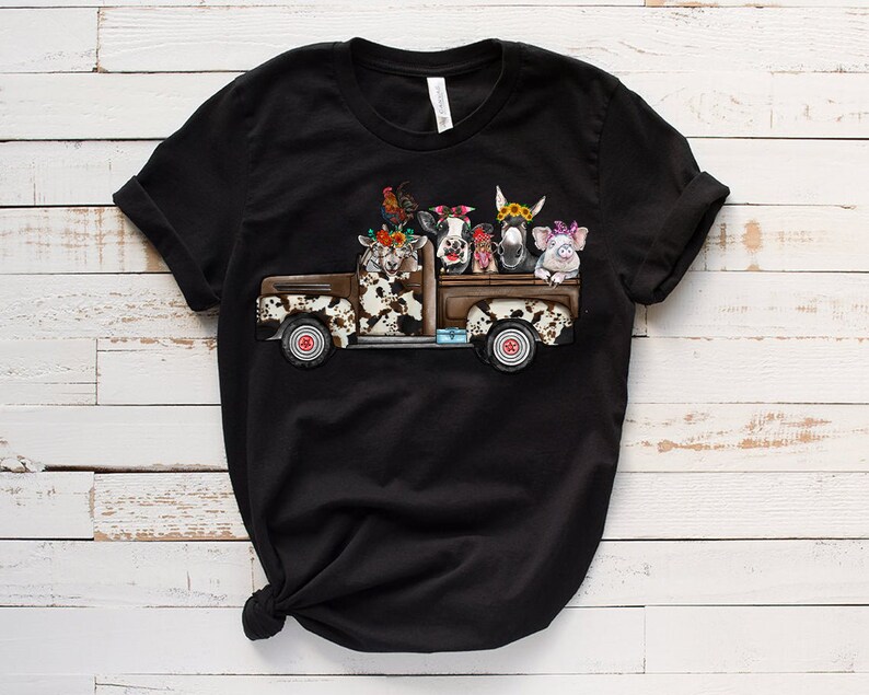 May include: Black t-shirt with a graphic of a vintage pickup truck filled with farm animals wearing flower crowns. The animals include a cow, a goat, a donkey, a pig, and a rooster.