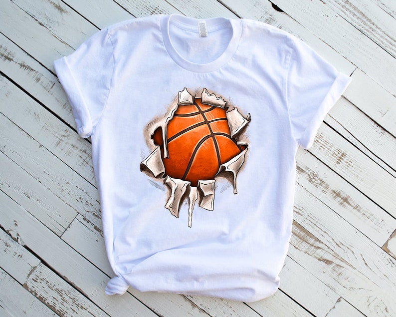 Peut inclure: T-shirt blanc avec un motif de ballon de basket qui &eacute;clate &agrave; travers le tissu. Le ballon de basket est orange et marron.