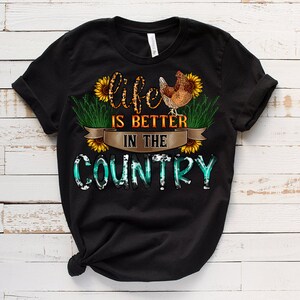 May include: Black t-shirt with a graphic design of a chicken, sunflowers, and the text "Life is better in the country".