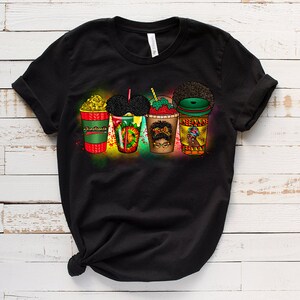 May include: Black t-shirt featuring a graphic of five colourful cups with different designs. The cups are arranged in a row and have a variety of toppings, including whipped cream, sprinkles, and fruit. The graphic is surrounded by a colourful spray paint effect.