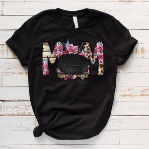 May include: Black t-shirt with a floral design and a hockey puck. The design spells out "MOM" with the hockey puck in the center.