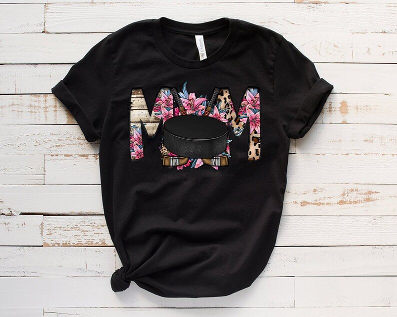 May include: Black t-shirt with a floral design and a hockey puck. The design spells out "MOM" with the hockey puck in the center.