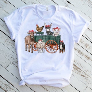 May include: White t-shirt with a graphic of a farm scene. A cow, pig, donkey, chicken, sheep, and dog are all wearing red bandanas and riding in a green wagon.