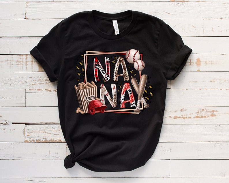 May include: Black t-shirt with a graphic design featuring the words "NA NA" in a red and white leopard print, baseballs, bats, and a box of peanuts.