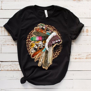 May include: Black t-shirt with a colorful Native American headdress design on a leopard print background.