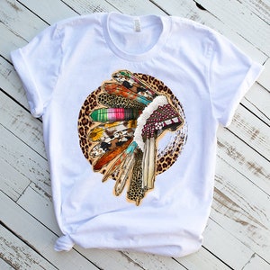 May include: White t-shirt with a colorful Native American headdress design on a leopard print background.
