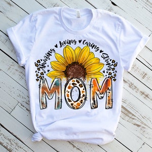 May include: White t-shirt with a sunflower graphic and the text "Amazing Loving Caring Strong Mom".