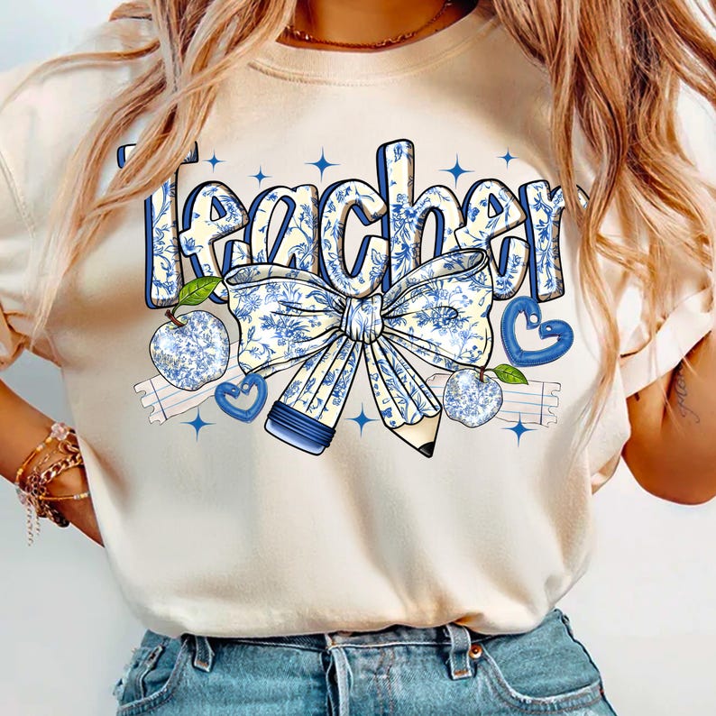 May include: A white t-shirt with the word "teacher" printed in blue and white floral lettering. The design includes a blue and white floral bow, a pencil, and apples.