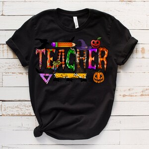 May include: Black t-shirt with a Halloween-themed graphic that says "TEACHER" with a witch's hat, broom, spider, and pumpkins.