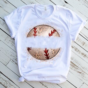 Puede incluir: Camiseta blanca con un gr&aacute;fico de un b&eacute;isbol con un dise&ntilde;o de estampado de leopardo. El b&eacute;isbol est&aacute; rodeado por un efecto de salpicadura blanca.
