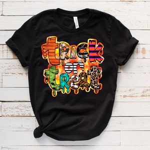 May include: Black t-shirt with a colorful "Trick or Treat" graphic design. The text is made up of different patterns and textures, including stripes, animal print, and polka dots.