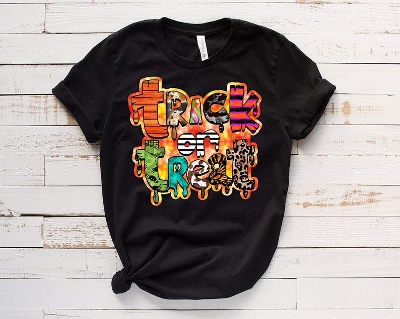 May include: Black t-shirt with a colorful "Trick or Treat" graphic design. The text is made up of different patterns and textures, including stripes, animal print, and polka dots.
