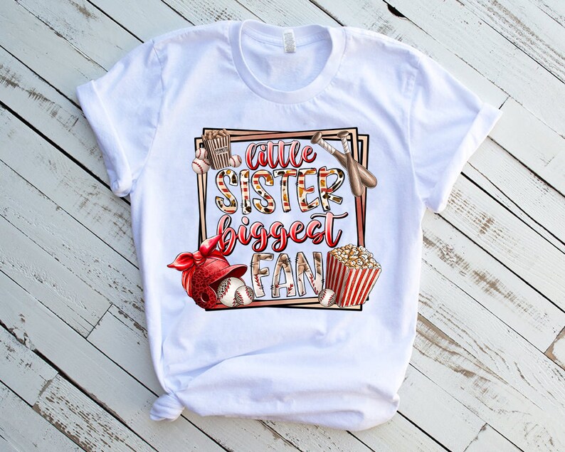 K&ouml;nnte beinhalten: Wei&szlig;es T-Shirt mit einem Grafikdesign eines Baseball-Themas. Der Text auf dem Shirt lautet "Little Sister Biggest Fan".