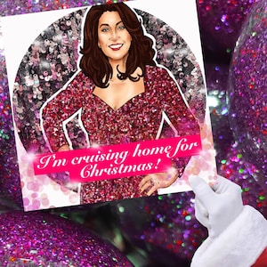 Puede incluir: Ilustración festiva de una mujer con un vestido de lentejuelas, con el texto "I'm cruising home for Christmas!". El fondo presenta un diseño brillante y con purpurina. La imagen está sostenida por una mano enguantada, sugiriendo un tema navideño.