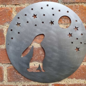 May include: A metal wall decoration featuring a penguin silhouette with a crescent moon and stars cut out. The decoration is painted in a silver finish.