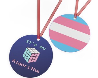 May include: Two round ornaments with red ribbon. One ornament is blue with a pixelated Rubik's cube and the text "It's my Algorithm". The other ornament is a blue, pink, and white transgender pride flag.