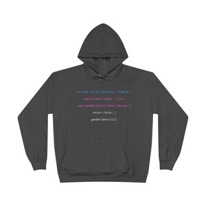 May include: Charcoal grey hooded sweatshirt with long sleeves. The front features computer code in blue and pink, including the text "private string identity = female". A relaxed, everyday garment.