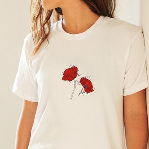 May include: A white t-shirt with a simple line drawing of two red poppies.