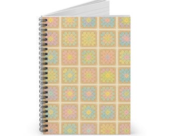 Pode incluir: Caderno espiral com um padrão floral colorido. A capa apresenta uma grade de flores em tons pastel em quadrados, com um fundo creme. A encadernação em espiral é preta.