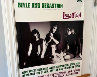 May include: A black and white promotional poster for the band Belle and Sebastian, featuring the text "Legalman" and the band members in a photo. The poster advertises a new single release, available on seven, twelve, and compact disc. The text also reads "Not taken from the forthcoming long-player, fold your hands child, you walk like a peasant."