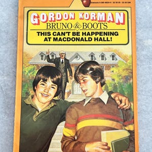 May include: A book cover with a yellow background and the title "Gordon Korman Bruno & Boots This Can't Be Happening At Macdonald Hall!" in red and black text. The cover features an illustration of three boys standing in front of a brick building.