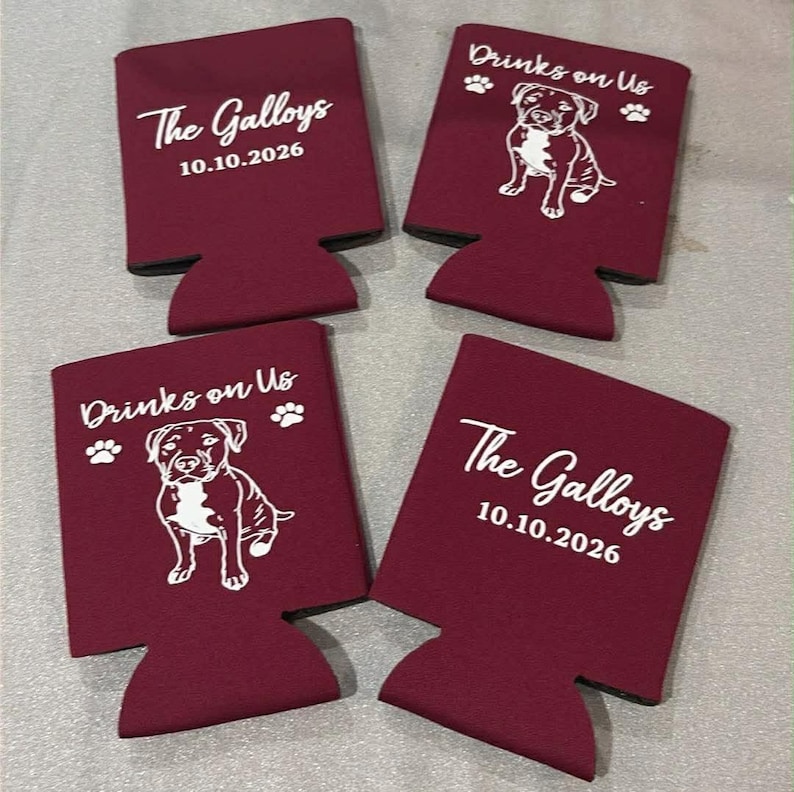 May include: Four maroon foam can coolers. Two feature the white text The Galloys and 10.10.2026. The other two feature the white text Drinks on Us, paw prints, and a line drawing of a dog. The items are arranged in a two-by-two grid pattern.