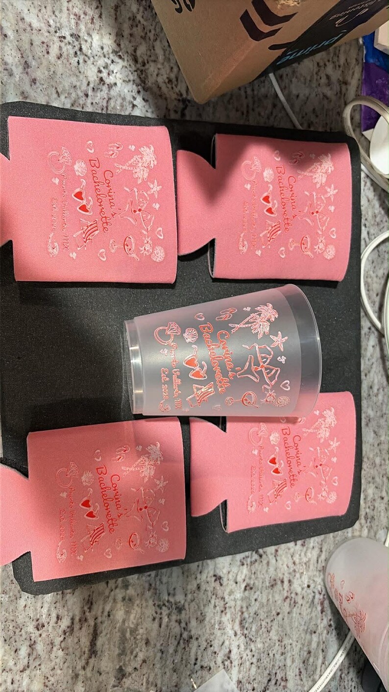 May include: Four pink foam can coolers and one translucent plastic cup, each printed with the text Corina's Bachelorette, Puerto Vallarta, MX, Est. 2020, alongside graphics of a diamond ring, palm trees, sunglasses, a beach chair, and a cocktail.