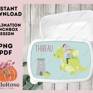 May include: A white lunchbox with a blue background and a cartoon illustration of a knight riding a green dragon. The text "THIBEAU" is printed in black on the lunchbox.