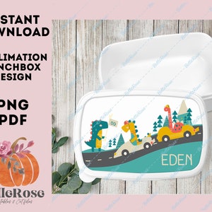 Puede incluir: Una fiambrera blanca con un diseño colorido que presenta tres dinosaurios conduciendo coches por una carretera. El texto "EDEN" está impreso en la fiambrera.