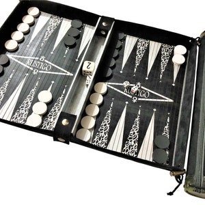 Könnte beinhalten: Ein Backgammon-Set in Schwarz und Weiß mit dem Wort "RUSTIGO" auf dem Spielbrett. Das Set enthält schwarze und weiße Spielsteine, Würfel und eine Tragetasche. Das Spielbrett ist geöffnet und spielbereit.
