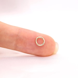 Op de afbeelding: Een kleine, ronde gouden buigring met een gladde, gepolijste afwerking. De metalen ring heeft een dunne, gelijkmatige band en een enkele zichtbare naad waar de twee uiteinden samenkomen, wat een eenvoudige, doorlopende lus vormt.