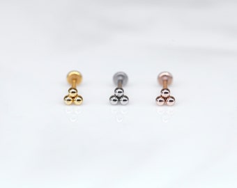 Puede incluir: Tres piezas de joyería corporal en oro, plata y oro rosa, cada una con tres pequeñas bolas.