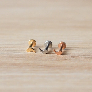 Puede incluir: Tres piezas de joyería corporal en forma de media luna en oro, plata y oro rosa.