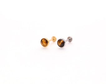 May include: Two gold and silver stud earrings with a round tiger's eye gemstone.