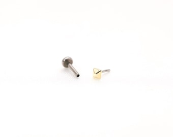 May include: A pair of body jewelry pieces. One is a silver barbell with a small ball on the end. The other is a gold pyramid-shaped stud.