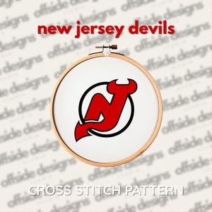 May include: A cross stitch pattern featuring the New Jersey Devils logo in red and black, set within a wooden embroidery hoop. The text "new jersey devils" is above the hoop, and "CROSS STITCH PATTERN" is below.