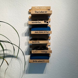 Könnte beinhalten: Wandregal aus Holz mit dem Text "Das Leben ist wunderbar, man muss es nur durch die richtige Brille sehen!!!"  Das Regal hat eine blaue Hülle und Sonnenbrillen.