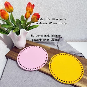May include: Two round, flat, crochet basket bases in pink and yellow. Each base has evenly spaced holes around the perimeter. The pink base is on the left, and the yellow base is on the right. The bases are on a wooden surface with a vase of flowers.