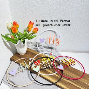 Puede incluir: Una colección de arte mural circular decorativo con la palabra "Hej" en varios colores, incluyendo naranja, amarillo y rosa. Cada pieza presenta un acento de corazón. Un jarrón de tulipanes se encuentra sobre una superficie de madera.