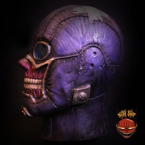 Pu&ograve; includere: Maschera dettagliata in viola e rosso con una superficie testurizzata e un grande occhiale. La maschera ha un aspetto usurato ed &egrave; realizzata in un materiale rigido.