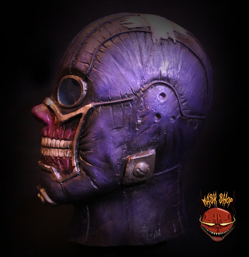 Pu&ograve; includere: Maschera dettagliata in viola e rosso con una superficie testurizzata e un grande occhiale. La maschera ha un aspetto usurato ed &egrave; realizzata in un materiale rigido.