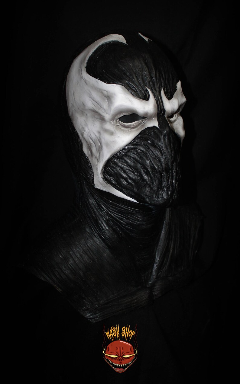May include: A black and white latex mask of a character with a skull-like face and a white, textured, skull-like design on the forehead. The mask is a full-face mask and covers the entire head. The mask is made of latex and has a realistic look.