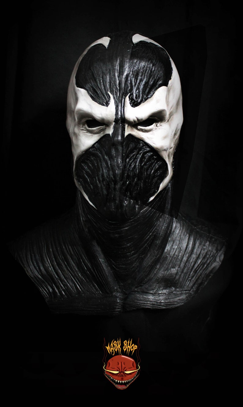 May include: A black and white latex mask of a superhero character with a skull-like face. The mask has a textured surface and a black and white color scheme. The mask is a popular character from comic books and movies.