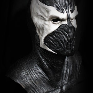 May include: A black and white latex mask of a character with a detailed, textured design. The mask covers the head and neck, with a white face and black eyes.